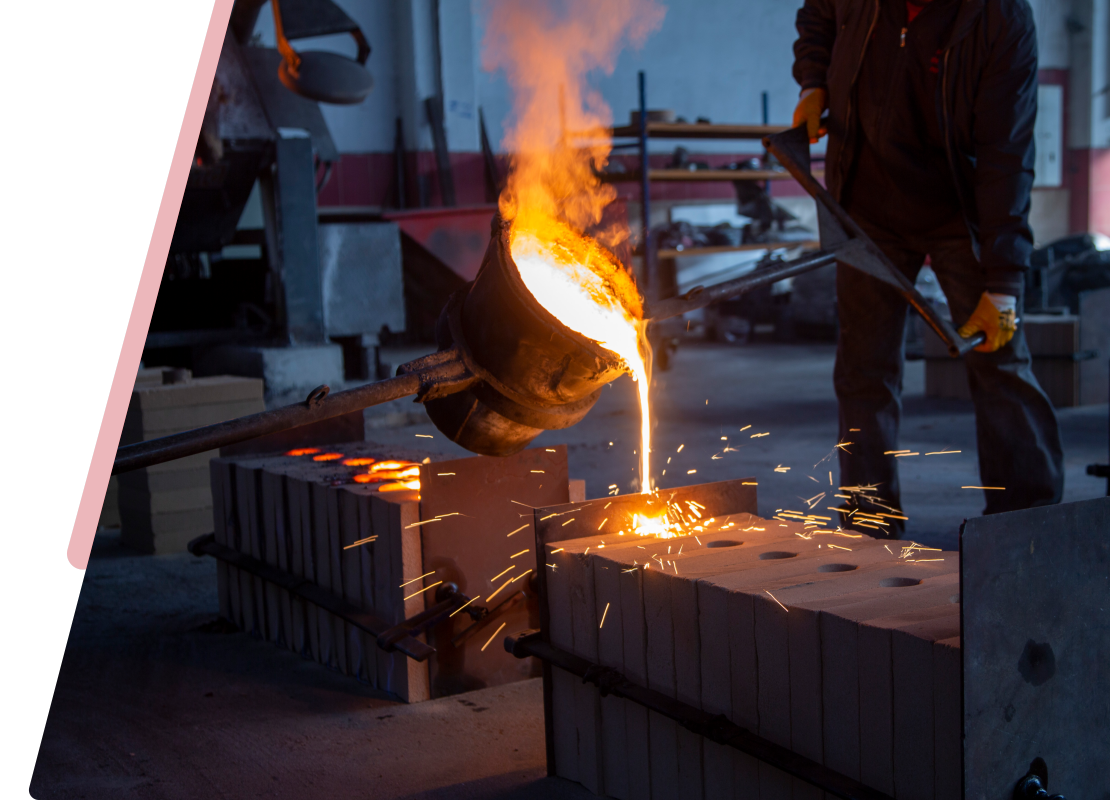 A worker pours molten metal into molds in an industrial foundry setting, with sparks flying.
